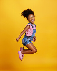 Excited, jump and happy girl child jumping in happiness, joy and smile while isolated in a studio...
