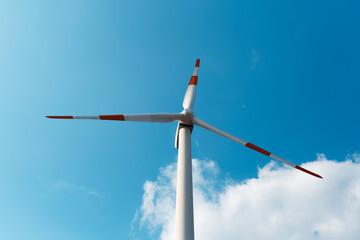 Close-up down view of wind turbine on background of blue sky. Windmill generating green energy.