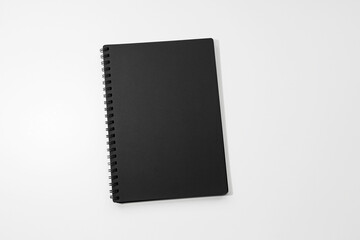 Close-up of black closed notebook on white background.