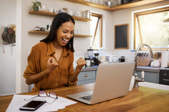 Laptop, success and business woman celebrating finance, savings and investment growth in a kitchen. Online, victory and freelance female excited for good news, loan and startup approval in her home