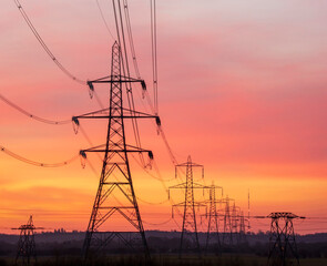 Silhouette electric pylons against an orange sky