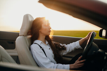 young beautiful woman in a white shirt sitting in a red car cabriolet with a white interior. red...