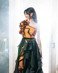 A woman in an orange dress is standing in front of a door