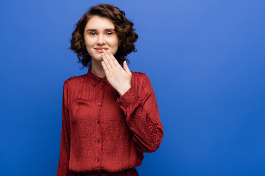 happy young woman telling thank you on sign language isolated on blue.