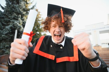 Excited male student in mantle scream graduate from university finish course studying. Happy man triumph holding college diploma in hands overjoyed with high school graduation. - obrazy, fototapety, plakaty