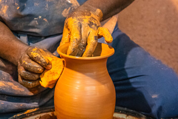 Gros plan sur les mains d'un homme qui fabrique une poterie en argile.