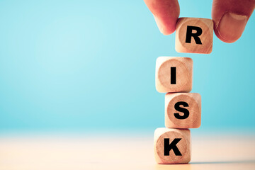 Hand putting risk wording print screen on wooden block cube for financial banking risk analysis and...