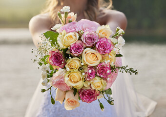 Closeup, bride and flower bouquet outdoor for celebration of commitment, ceremony and marriage. Woman, wedding and holding roses, spring flowers and floral blossom to celebrate love at elegant event