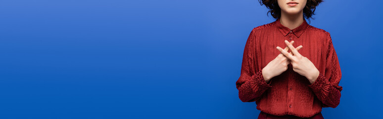 partial view of teacher in red blouse gesturing on sign language isolated on blue, banner.