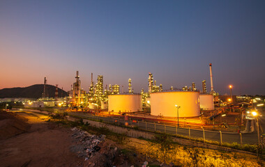 Obraz premium Twilight scene of oil refinery plant and storage white tank oil of Petrochemistry industry