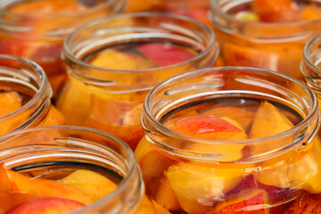 Close up of fresh, ripe, organic peach slices in fruit jars with water and sugar added, ready to be canned.
