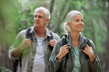 Elderly couple, hiking and active seniors in a forest, happy and relax while walking in nature....