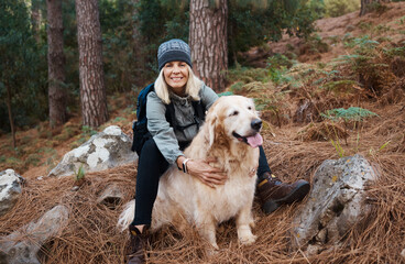 Adventure, explore and woman hiking with her dog, pet or animal in the winter forest for exercise, workout or fitness. Trekking, travel and elderly or senior female trekking in the woods on holiday