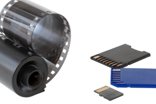 Micro SD card against vintage roll film in reel, on isolated background