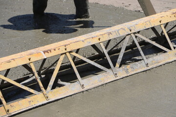 This impressive photo showcases a vibratory truss screed in action, using its powerful vibrations to expertly smooth fresh concrete. Perfect for construction and engineering projects.