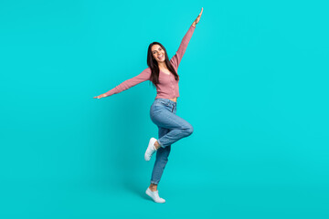 Fototapeta na wymiar Full size photo of satisfied nice girl raise hands stand one leg dancing good mood isolated on teal color background