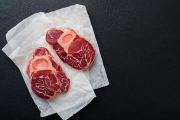 Osso Buco raw steak meat. Barbecue meat. Raw fresh cross cut veal shank and seasonings pepper, rosemary, thyme and salt on dark background. Beef Leg Slice . Italian menu. Top view.