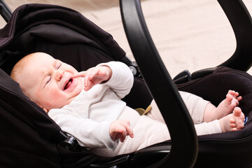 toddler baby lies in a car seat