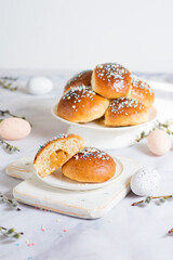 Easter buns with caramel filling. The foreground shows a section of a bun. On a light background with Easter attributes - eggs and willow branches