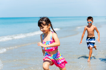 Group of Diversity little child boy and girl friends running and playing sea water at tropical beach together on summer vacation. Happy children kids enjoy and fun outdoor lifestyle on beach holiday.