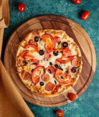 Italian pizza with sausage, olives, tomatoes and cheese