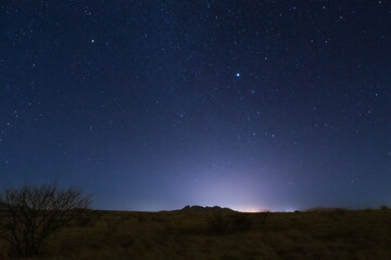 The starry night sky appearing at the end of daylight over the landscape.