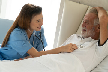 Fototapeta premium A nurse is listening to the heart rate of an old male patient. Inside the nursing home