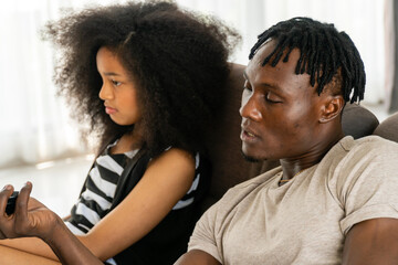 A black father playing games with his daughter in the living room.