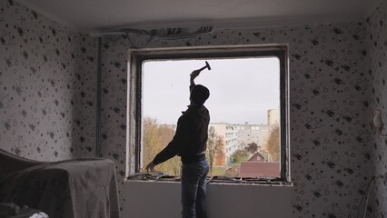 An employee removes an old wooden window.