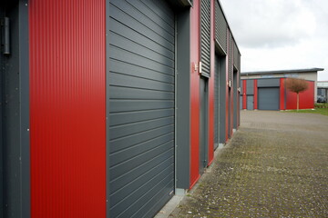 Moderne Architektur eines Gewerbebau in Rot und Grau mit modernem Segmenttor vor blauem Himmel im...