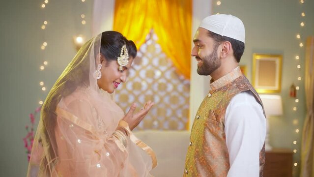 Closeup shot of indina muslim couple celebarting eid or ramadan by wishing each other at home - concept of islamic festival, treditional and reletionship.