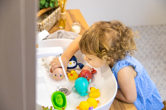 The child washes toys in the bathroom. Selective focus.