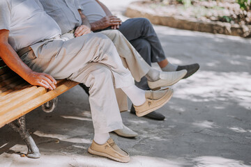 Pensioners grandfathers sit on bench and smoke cigarettes. Matured men, friends.
