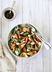 Salad with figs, tomatoes, nuts, cheese, greens, plums and sprinkled with honey