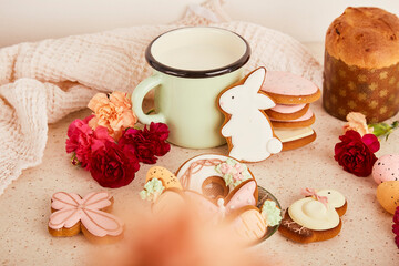 Aesthetic cozy Easter table with milk mug with glazed cookies, Cake and flowers. Springtime holiday floral background.