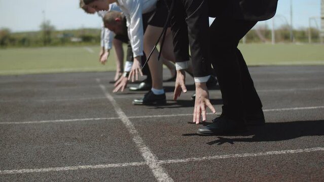 Businessmen stand on starting line of stadium preparing for the race, close-up of the legs. Concept business competition