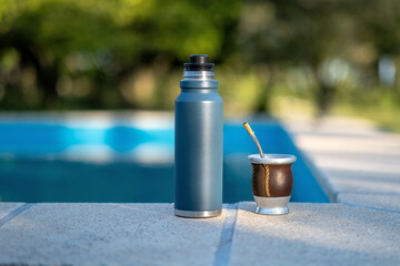 Mate and a thermos on the edge of a pool