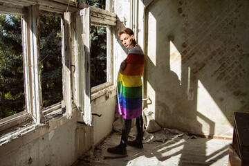 Fototapeta na wymiar Sadness, pain and loneliness. Young attractive guy with a gay flag.