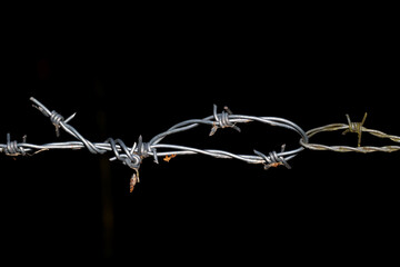 Rusty Barbed wire fence with black background