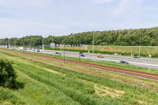 Motorway running parallel to railway tracks in the countryside of Netherlands on a summer day