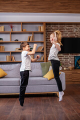 Fototapeta na wymiar Children jump and dance at home while listening to music on headphones. Having fun. Family concept.