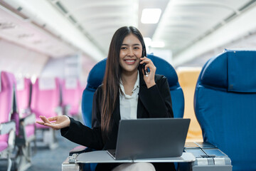 attractive businessman in suit with talking on mobile phone and working on laptop while sitting in airplane cabin. Work and travel concept