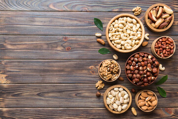 mixed nuts in wooden bowl. Mix of various nuts on colored background. pistachios, cashews, walnuts, hazelnuts, peanuts and brazil nuts