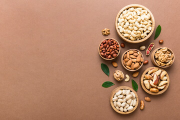mixed nuts in wooden bowl. Mix of various nuts on colored background. pistachios, cashews, walnuts, hazelnuts, peanuts and brazil nuts