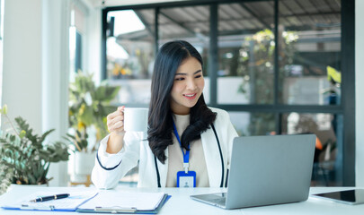 Asian businesswoman smiling happily with a new morning holding a cup of coffee lightly sipping coffee professional woman in size working in the office