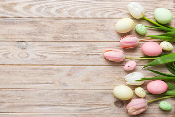 Happy Easter composition. Easter eggs on colored table with yellow Tulips. Natural dyed colorful eggs background top view with copy space