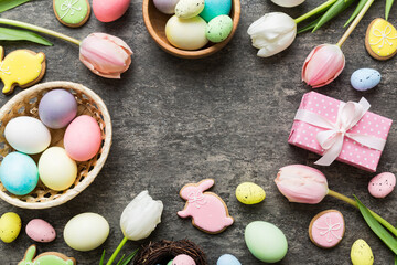 Easter frame with eggs, gift box and tulip on a colored background. The minimal concept. Top view Happy Easter composition. Card with a copy space of the place for the text