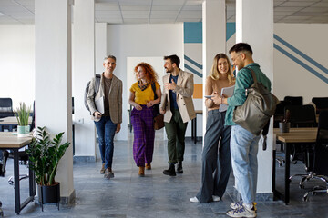 Fototapeta premium Happy business colleagues talking on the move in the office.