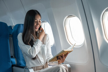 Business young asian woman talking on phone during for data financial report on airplane