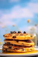 Syrup is poured down and chocolate chips are on top tall stack of golden pancakes layered on a plate with melted butter and syrup dripping down the sides of the stack. Generative Ai.